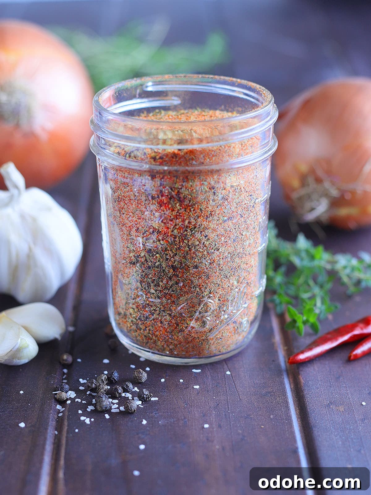 Homemade Cajun Seasoning Mix for Bold, Authentic Flavor 2 Homemade Cajun seasoning in a glass Mason jar with onions, garlic and seasonings in the background.