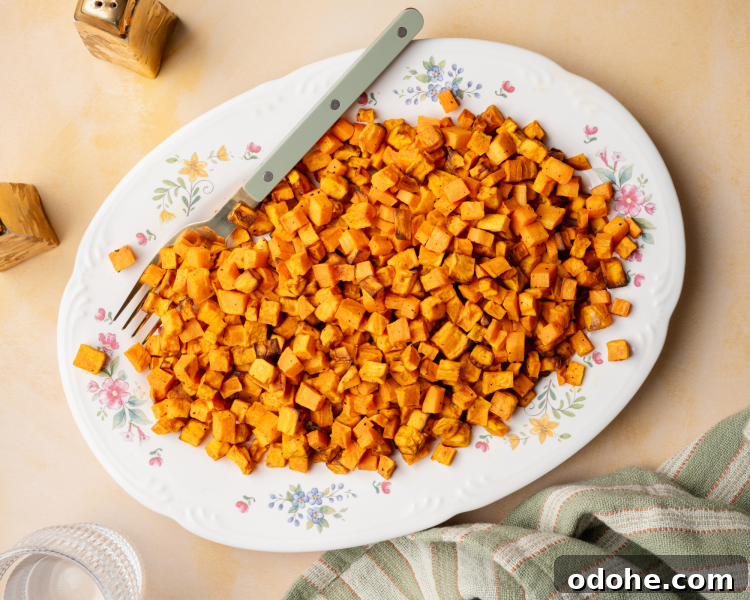 Cooked sweet potatoes served on a floral plate with fork on the side.
