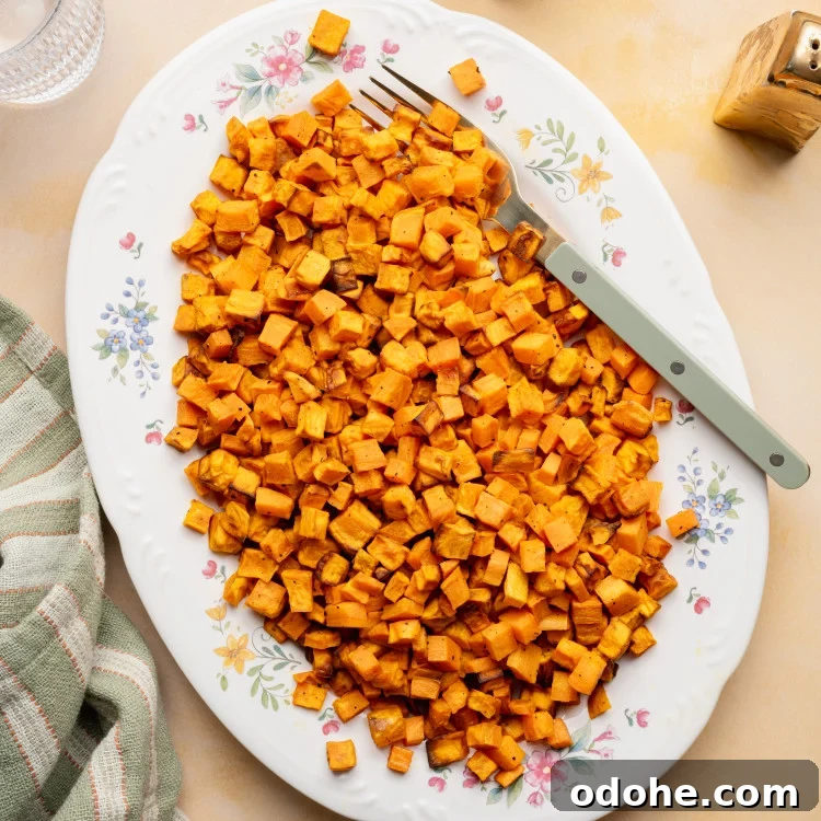 Cooked sweet potatoes on a large oval serving plate with fork on the right side.