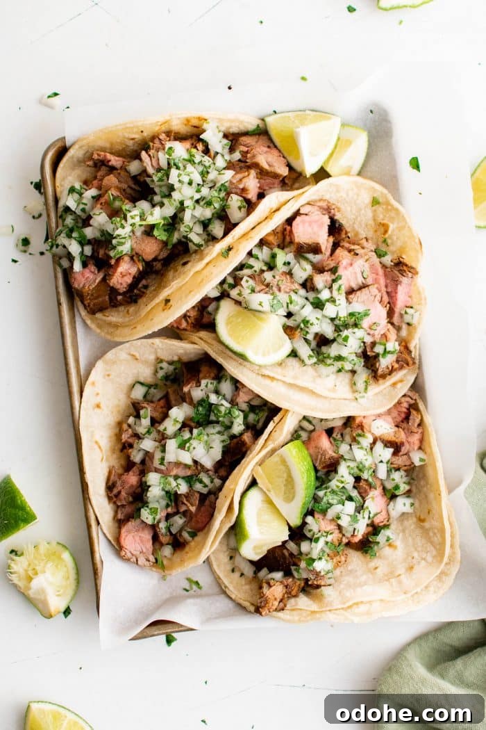 40+ Authentic Mexican Recipes for an Unforgettable Cinco de Mayo 16 Tray filled with four carne asada tacos made with corn tortillas and topped with a fresh onion, cilantro, and lime juice salsa.