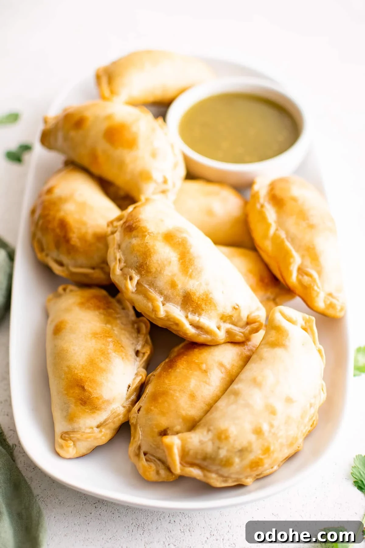 40+ Authentic Mexican Recipes for an Unforgettable Cinco de Mayo 24 A large oval plate piled with golden baked beef empanadas.