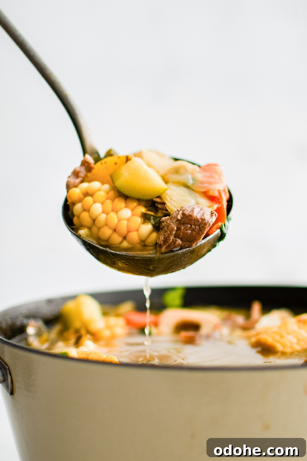 40+ Authentic Mexican Recipes for an Unforgettable Cinco de Mayo 32 Ladle filled with caldo de res with chunks of corn, zucchini, potato, and carrot.