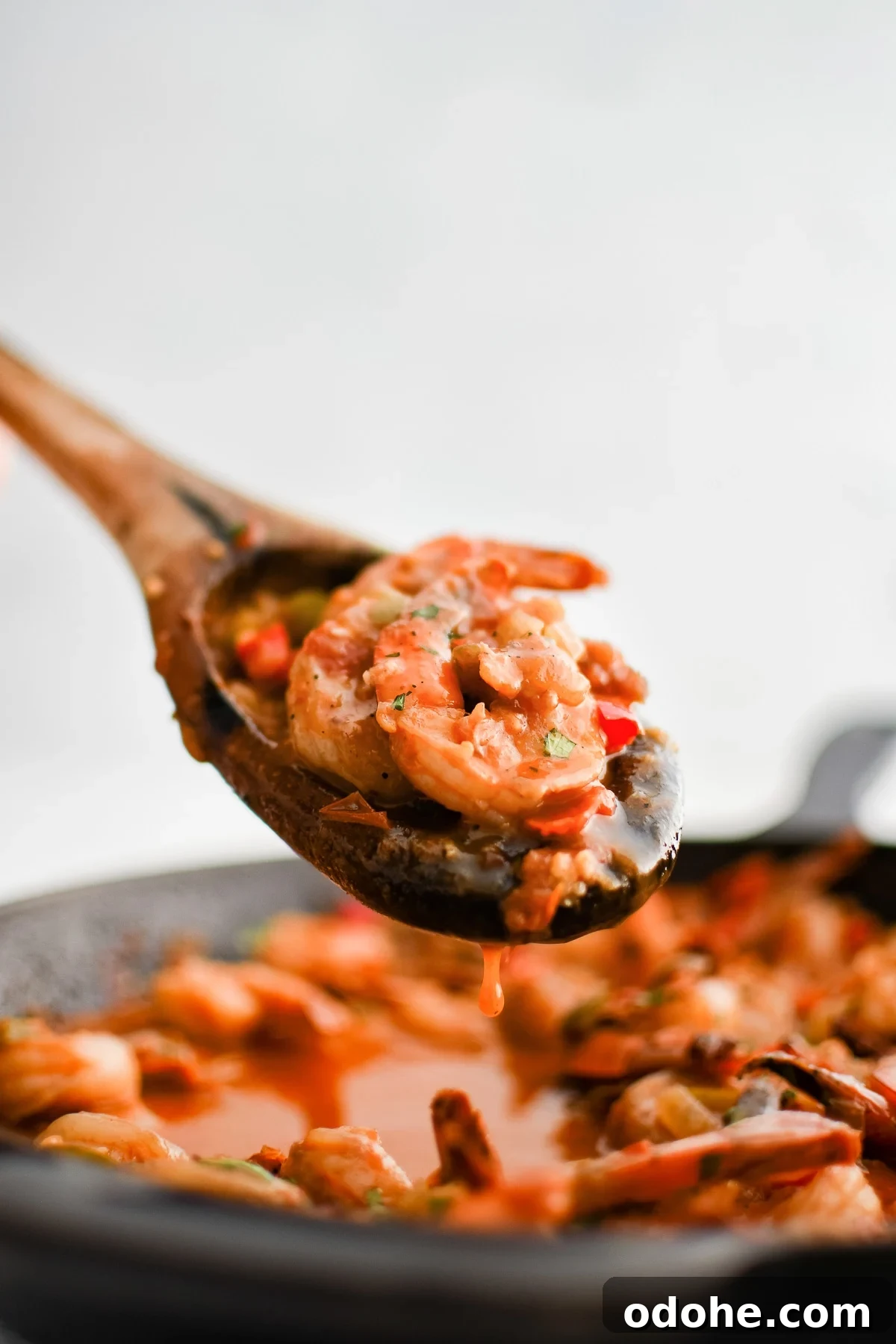 40+ Authentic Mexican Recipes for an Unforgettable Cinco de Mayo 41 Wooden serving spoon filled with cooked shrimp in a spicy chipotle sauce with onions and bell peppers.