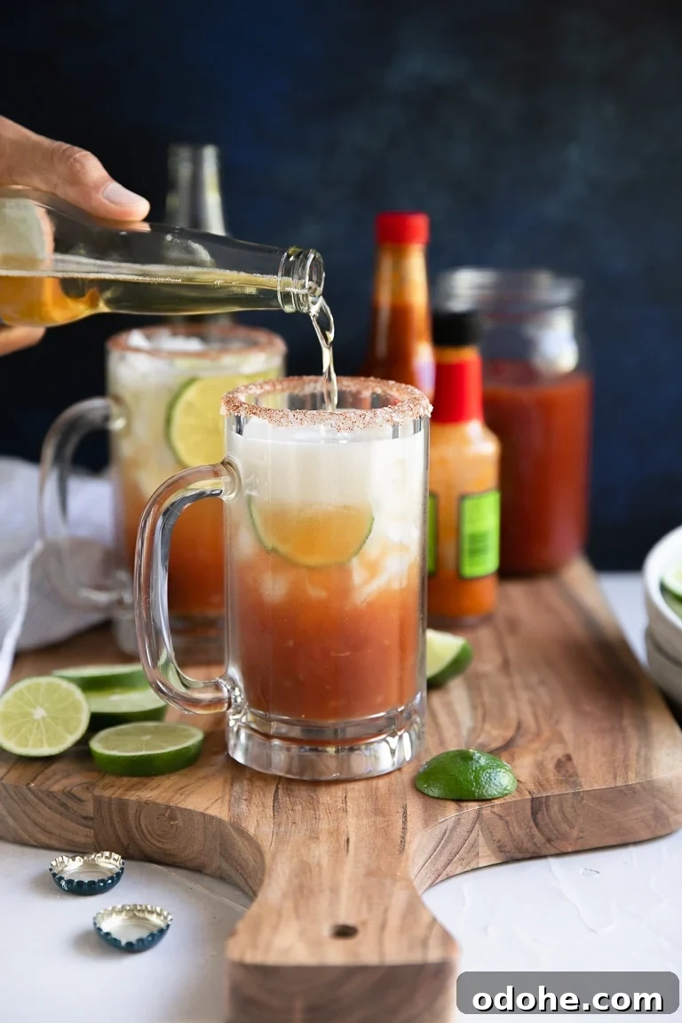 40+ Authentic Mexican Recipes for an Unforgettable Cinco de Mayo 44 Hand pouring beer into glass filled with ice, lime slices, and homemade clamato juice.