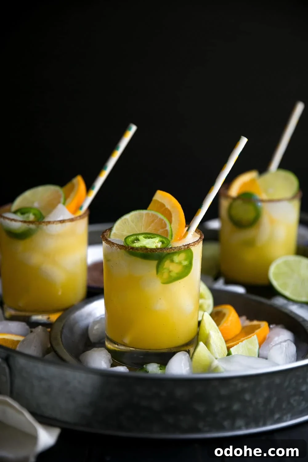 40+ Authentic Mexican Recipes for an Unforgettable Cinco de Mayo 45 Three glasses filled with Spicy Orange Margarita and garnished with fresh jalapeno, lime, and orange slices with a sweet and spicy chili salt rim.
