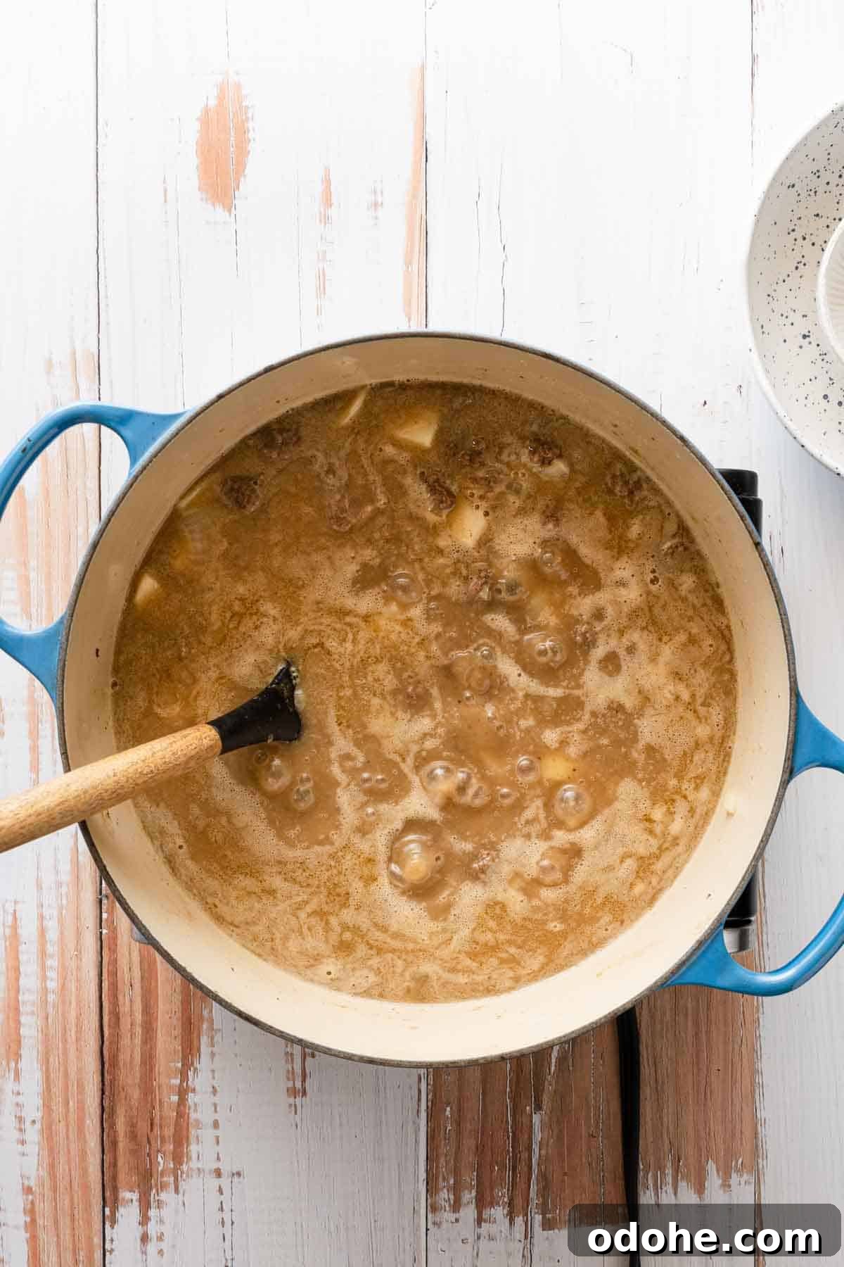 soup simmering with wooden spoon in pot.