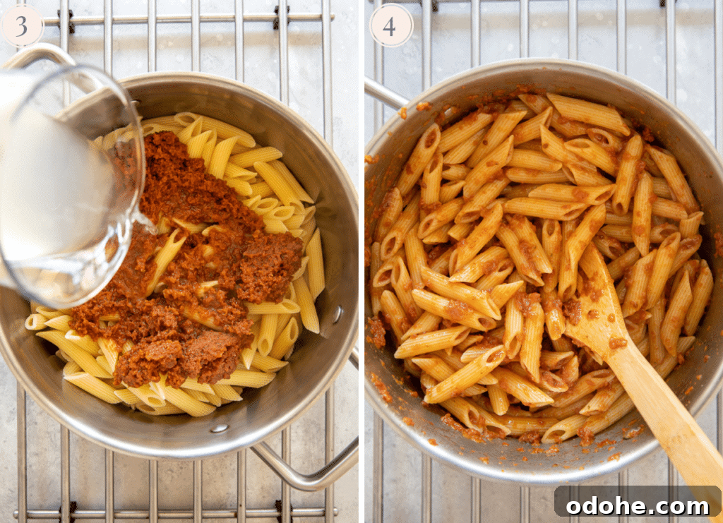sun-dried tomato sauce and pasta water being tossed with freshly cooked penne pasta