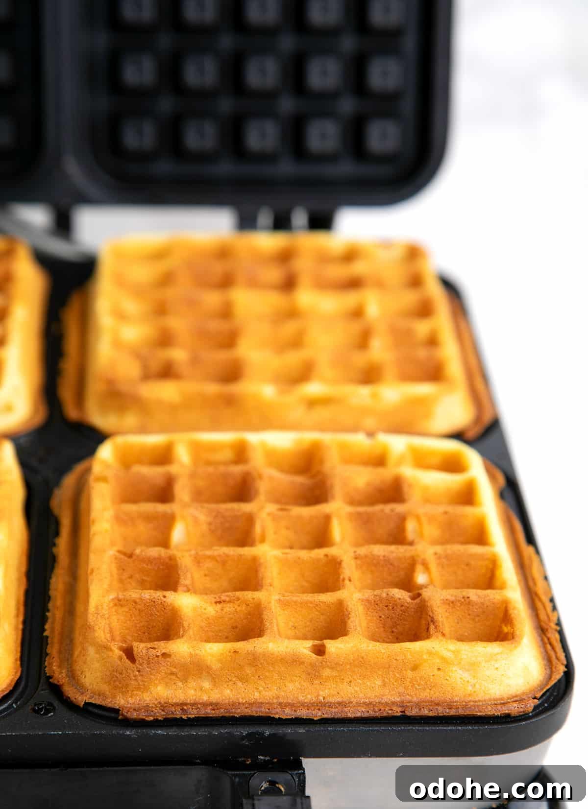 Two browned square waffles in waffle iron