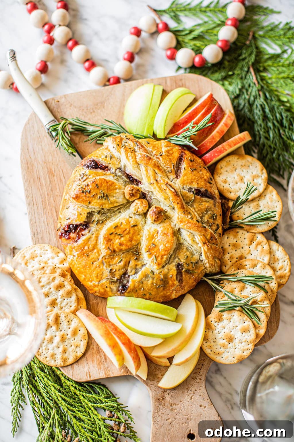 Warm Baked Brie with Cherry-Pecan Topping 6 Baked brie on a wooden serving board with apples and crackers.