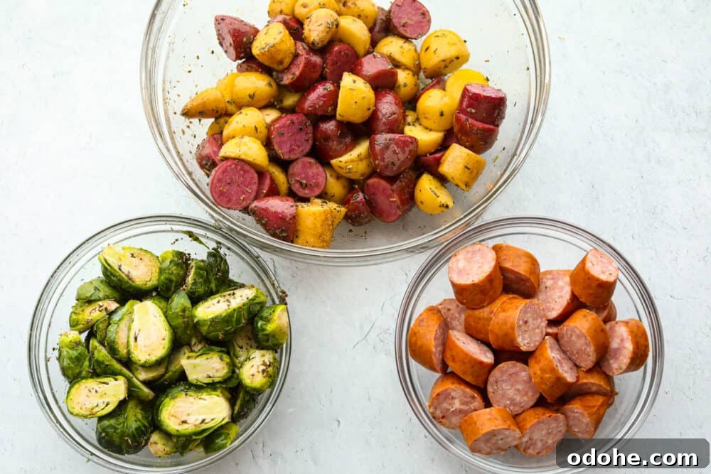Prep bowls with potatoes, Brussels sprouts and sausage Three glass bowls with cut potatoes, sliced Brussels sprouts and sliced sausage