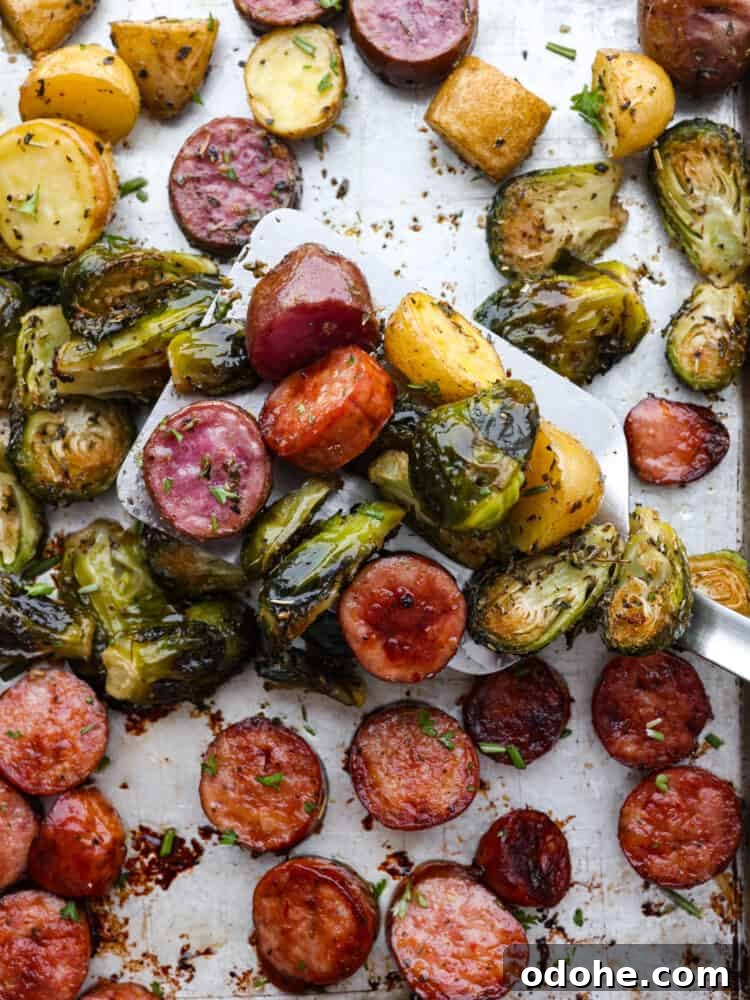 Serving sheet pan sausage and vegetables Close up of sausage and veggies being scooped with a spatula
