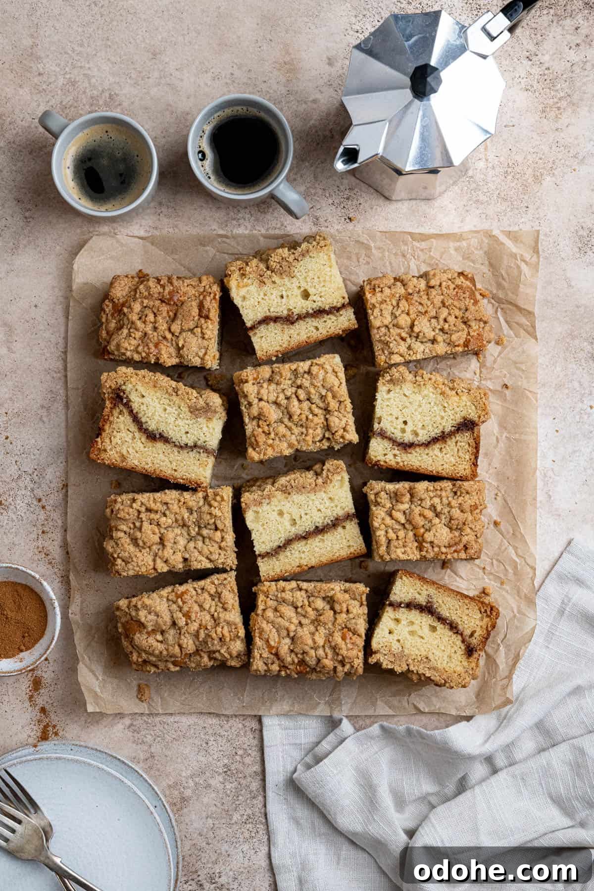 Vegan coffee cake on a sheet of baking paper with a pot of coffee and two espresso cups.