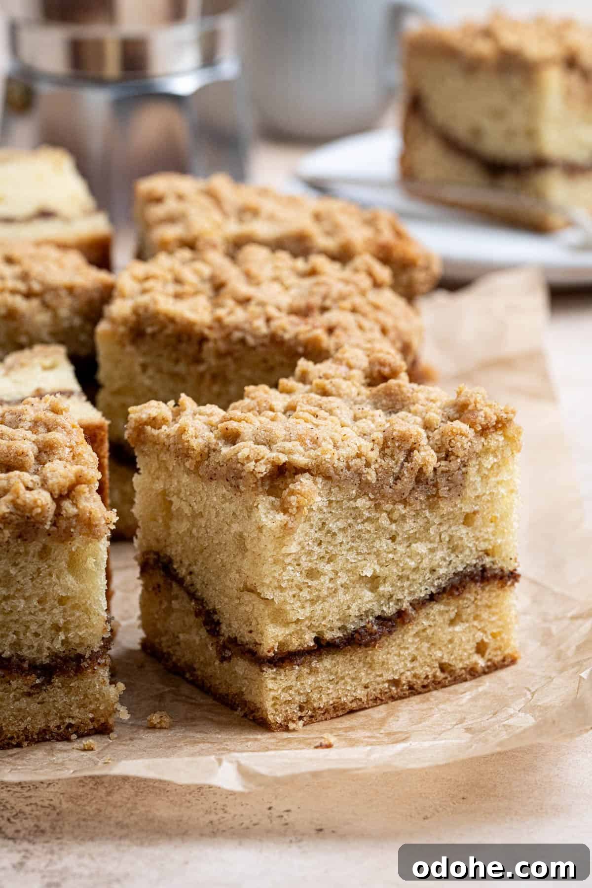 Close up of a square of vegan coffee cake on a sheet of baking paper.
