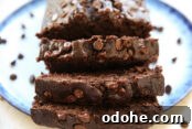 Banana chocolate bread sliced and sitting on a plate with chocolate chips scattered around the bread.