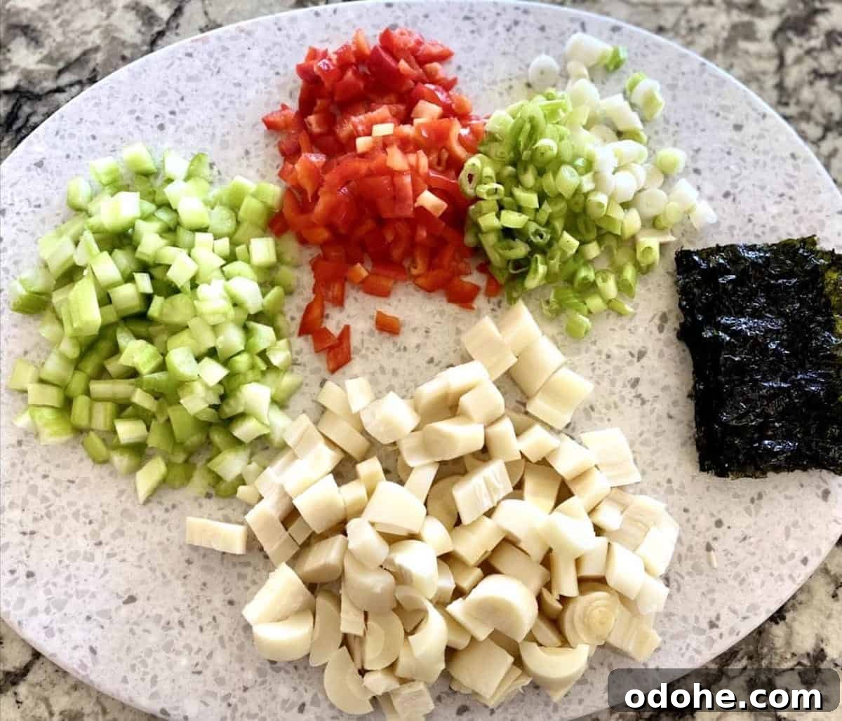 Hearts of Palm Vegan Lobster Roll Recipe 3 Green onions, red bell pepper, celery, hearts of pam and seaweed on a cutting board.