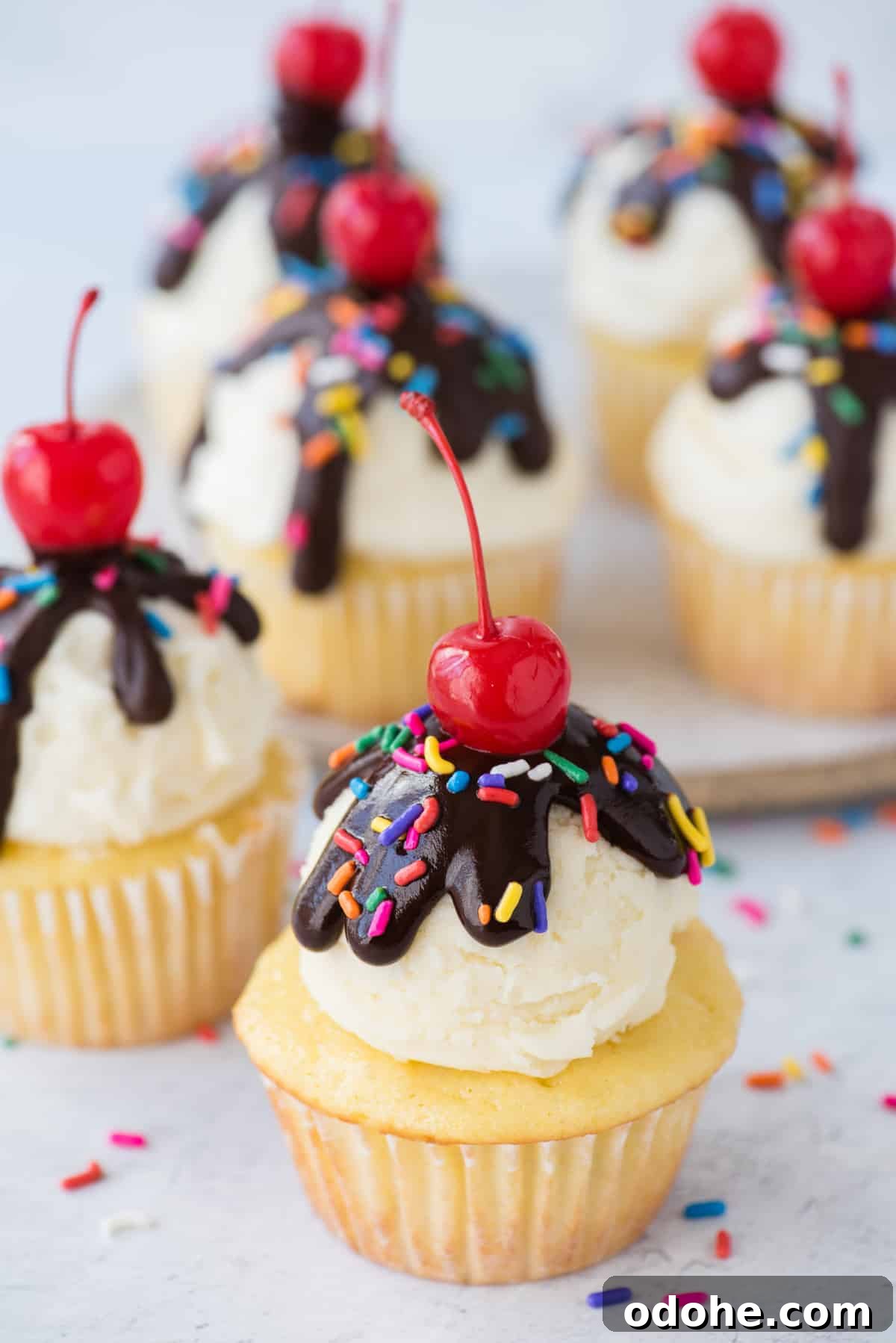 Ice Cream Cupcakes Recipe: Creamy No-Bake Dessert Cups 3 birthday cupcake with scoop of vanilla frosting, chocolate ganache drizzle, sprinkles and maraschino cherry on white background
