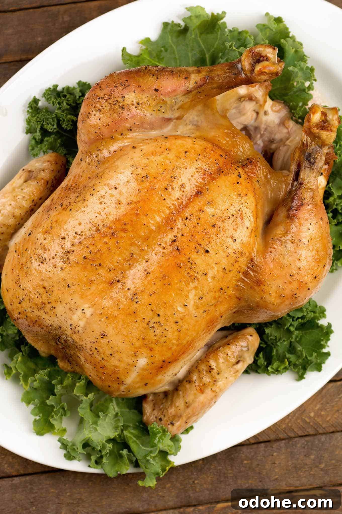 Herb-Roasted Capon with Garlic and Lemon 2 An overhead view of a roasted capon on a bed of green kale, ready to be carved for serving.
