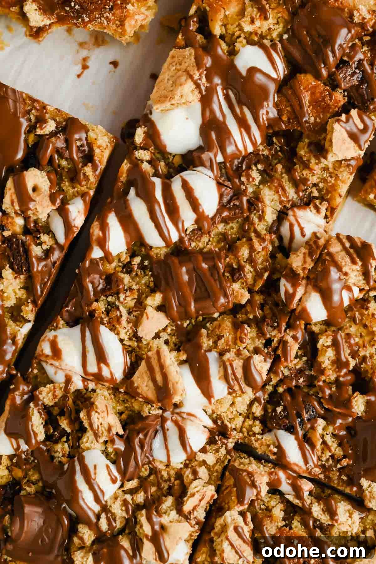 sliced s'mores casserole drizzled with melted chocolate on parchment.