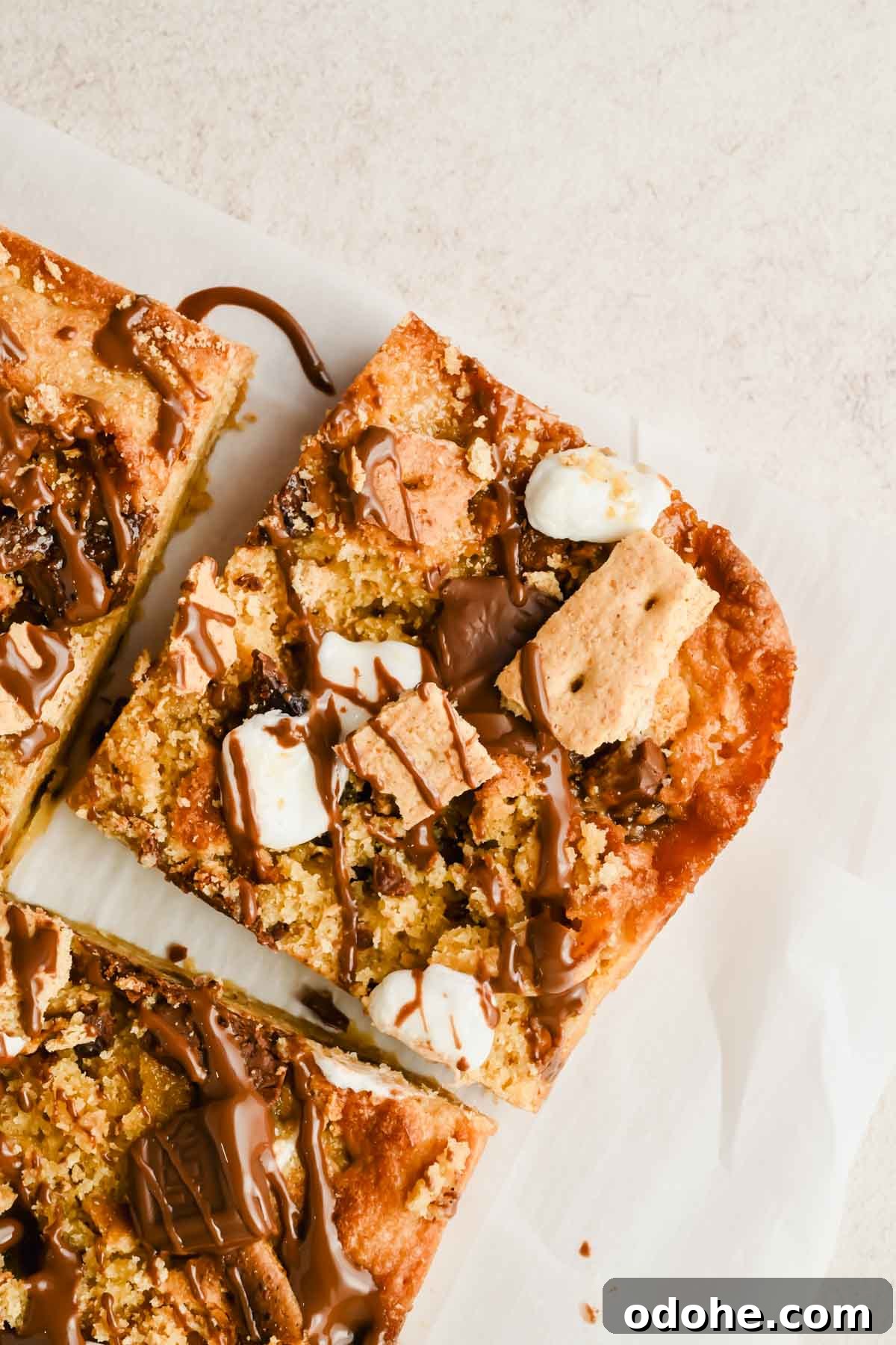 sliced s'mores casserole drizzled with melted chocolate on parchment.