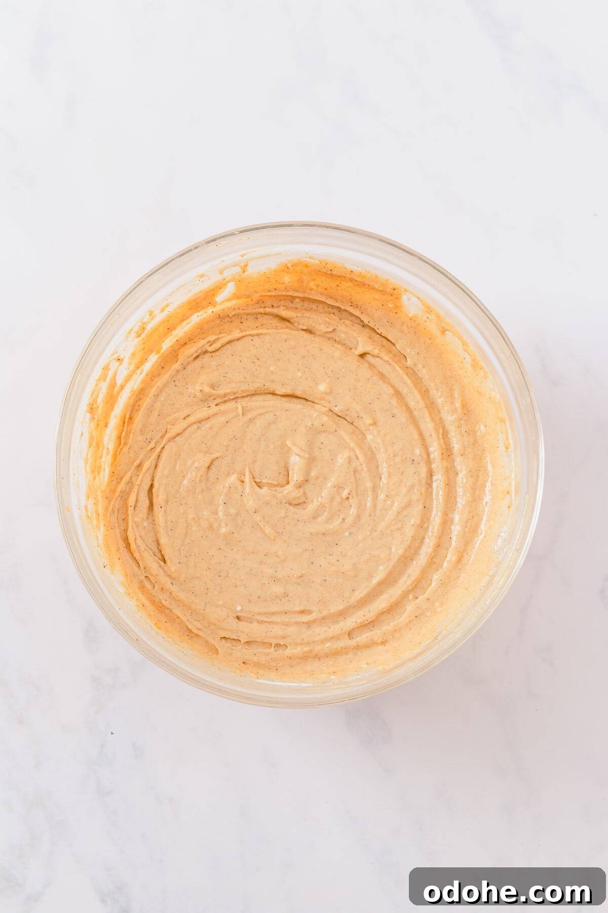 Smooth, creamy pumpkin dip beaten together in a glass bowl ready to chill.