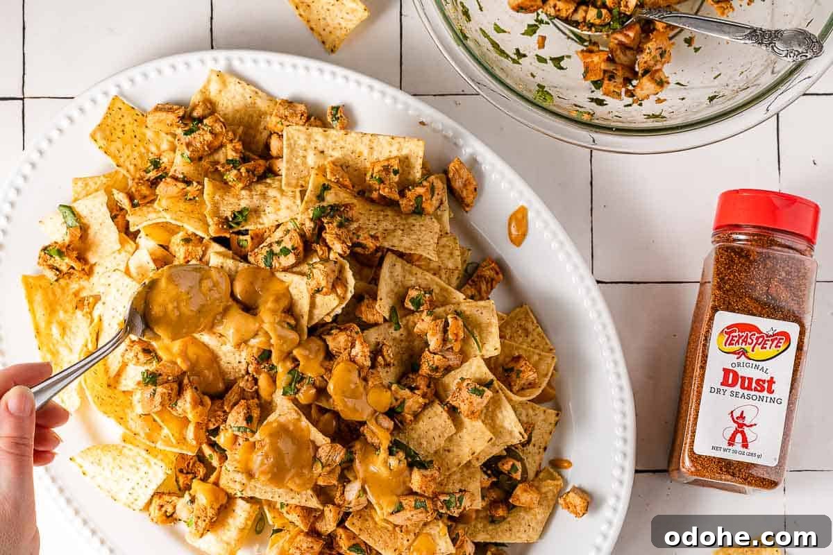 Crispy Spicy Queso Chicken Nachos Recipe 7 spoon drizzling queso on platter of nachos