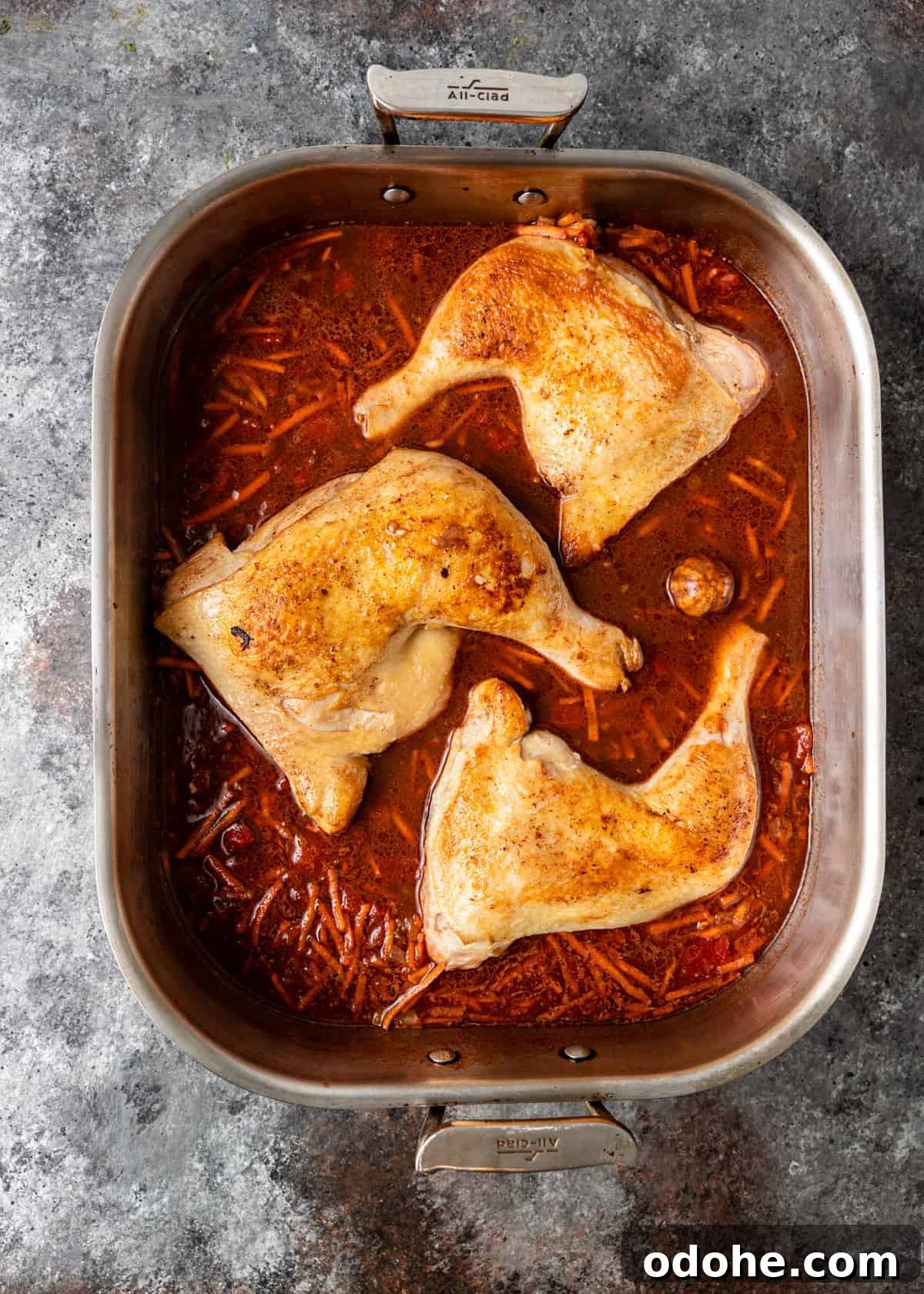 Authentic Kabsa: Arabic Chicken and Rice Recipe 7 overhead: pan seared chicken quarters in roasting pan with uncooked rice and tomato sauce