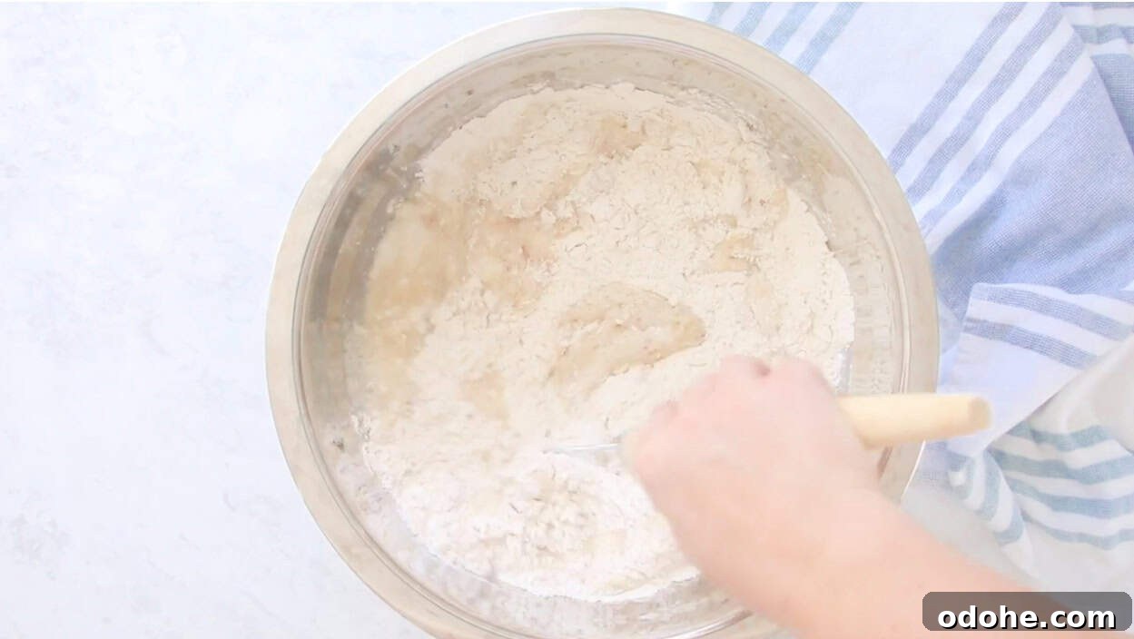 Apple Cinnamon Pull-Apart Bread Recipe 5 Hand stirring bread dough in large metal bowl.