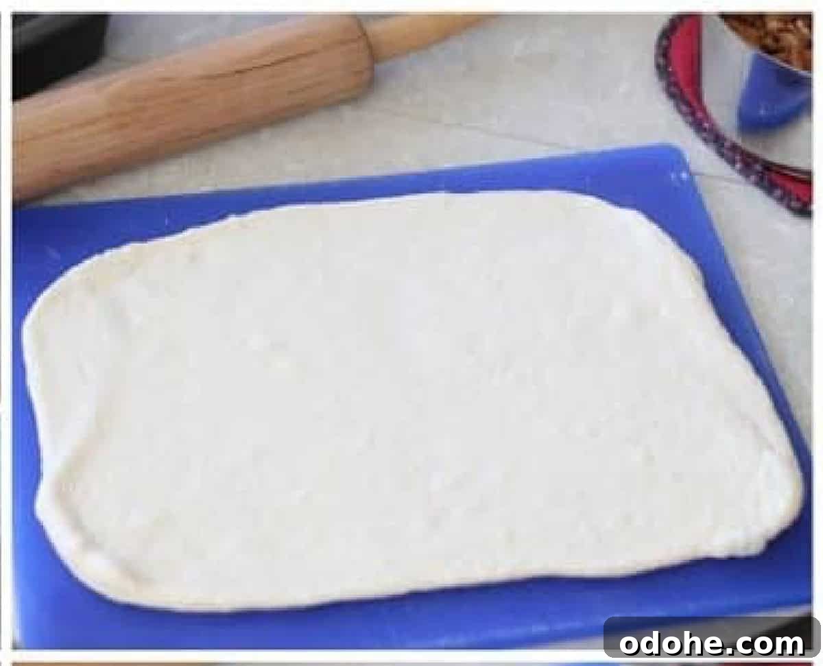 Apple Cinnamon Pull-Apart Bread Recipe 9 Blue cutting board with dough rolled out into a rectangle.