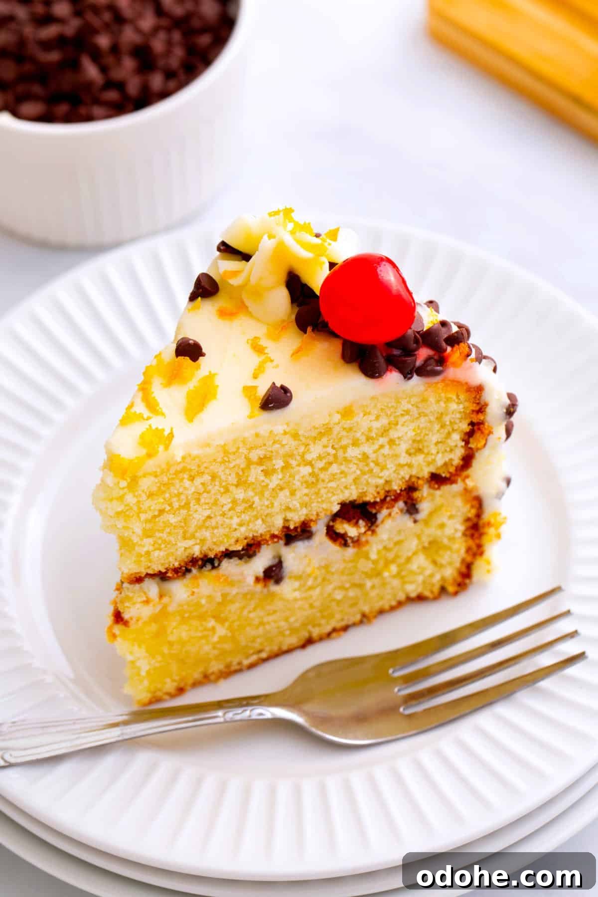 Cannoli Cake Recipe: Ricotta Filling and Chocolate Chips 9 slice of cannoli cake sitting on a white round plate.