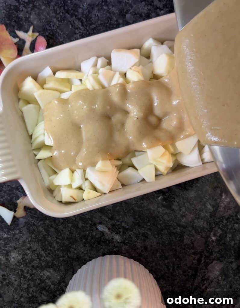 pouring batter over the apples in the pan